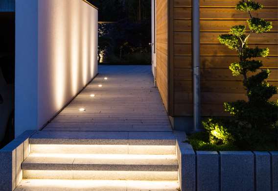 Lav granit mur og trappe med lys designet af havearkitekt Tor Haddeland